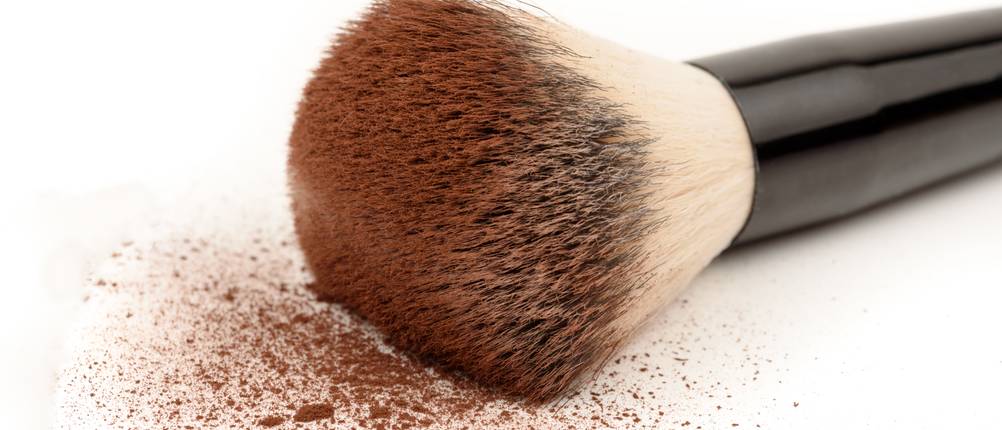 Zmile-Cosmetics-Test: Ein Pinsel mit Puder/Bronzer darauf, wobei sich die Partikel auf weißen Untergrund befinden.
