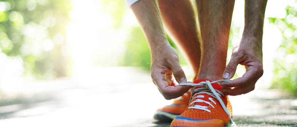 Brooks-Laufschuhe-Herren-Test: Ein Mann bindet weiße Schnürsenkel.