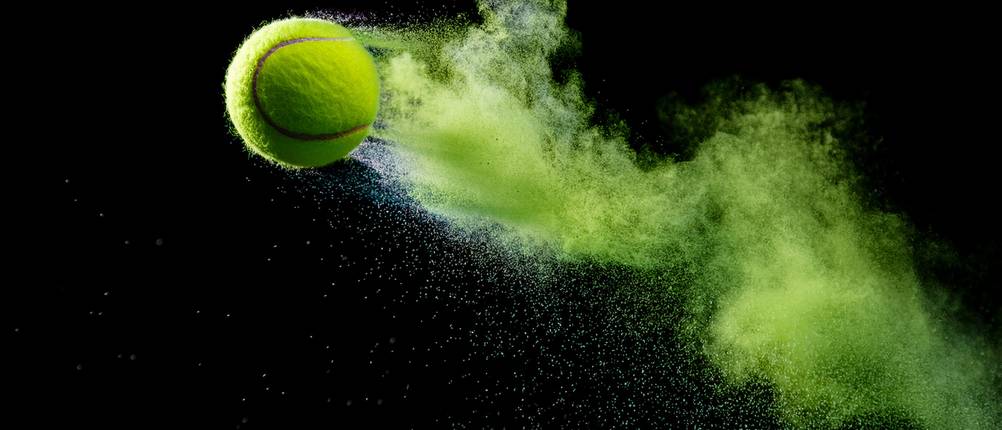 Tennisballmaschine-Test: Ein Tennisball fliegt vor einem schwarzen Hintergrund durch die Luft.