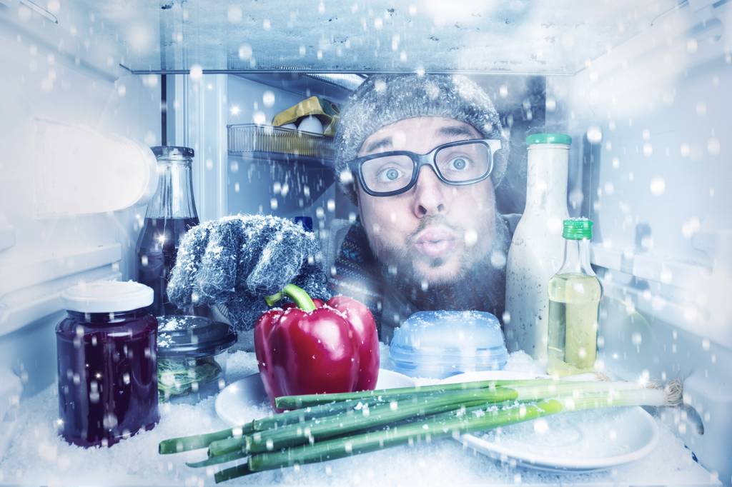 AEG-Kuehlschrank-Test: Ein Mann schaut in einen Kuehlschrank, in dem es schneit.