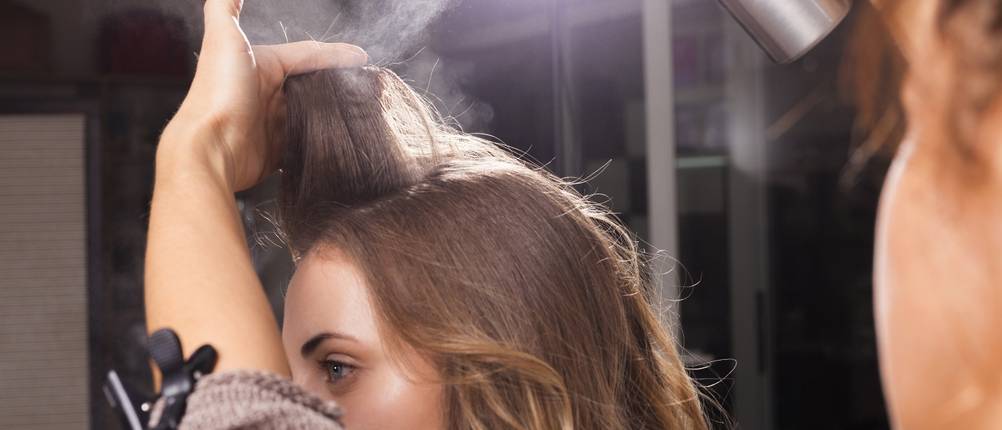 Toupierbürste-Test: Haarspray wird an einer Haarsträhne aufgetragen.