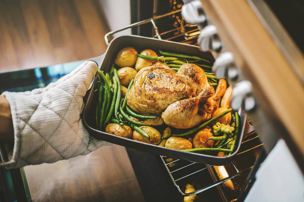 Beko-Herd im Test: Ein Hühnchen mit Bohnen wird in einer Kasserrole aus dem Backofen gezogen.