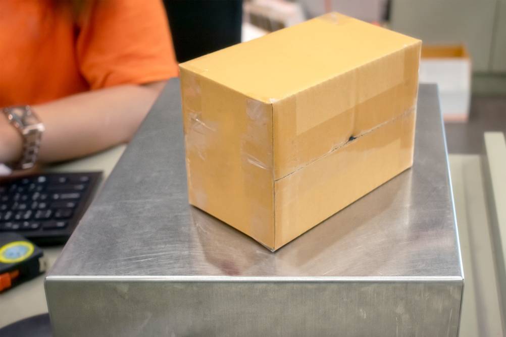 Paketwaage im Test: Eine Edelstahl-Plattformwaage neben einer Tastatur die von einer Person bedient wird.