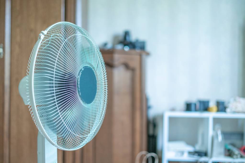 Brandson-Standventilator im Test: Ein weißer Standventilator steht in einem Wohnraum, der einen etwas verschwommenen, chaotischen Hintergrund bildet.