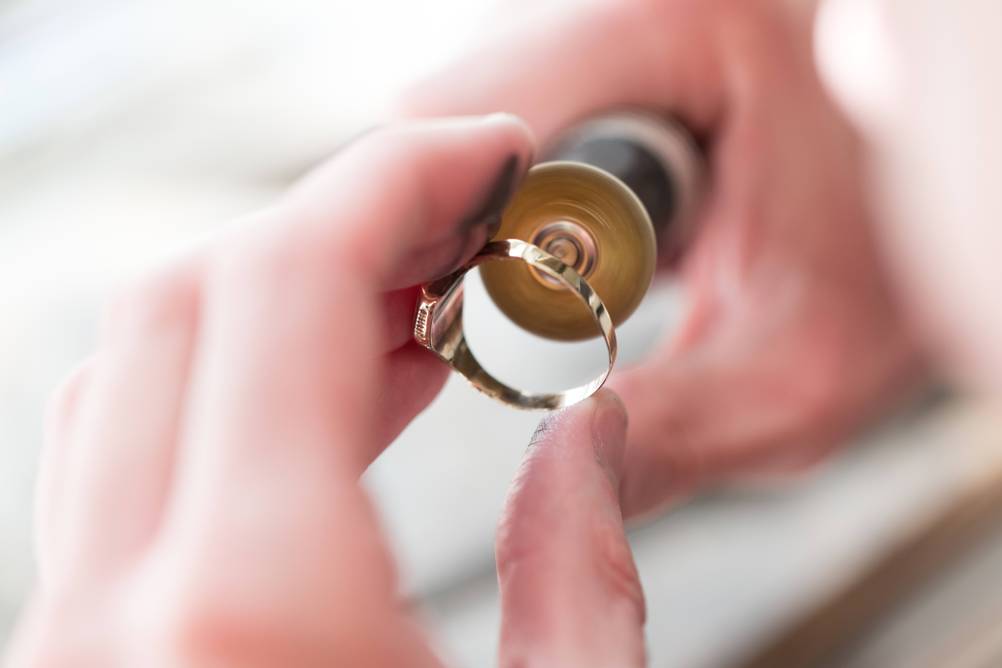 Sandstrahlgerät im Test: Ein Goldring wird mit einem kleinen drehenden Multitool bearbeitet.