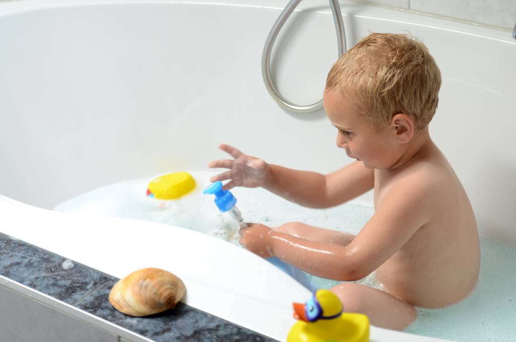 Durchlauferhitzer mit Fernbedienung im Test: Ein Kleinkind sitzt in einer Badewanne und spielt im schaumigen Wasser mit einem Seifenspender.