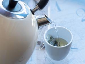 Wasserkocher-Test: Wasserkocher füllt aufgekochtes Wasser in eine Tasse ein.