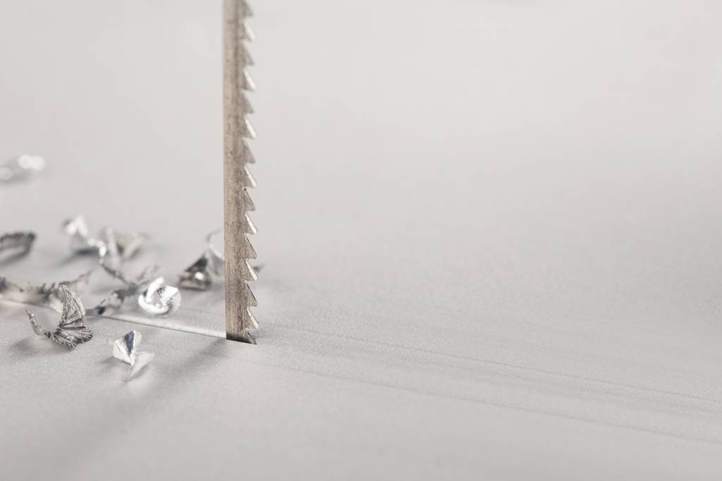 Stichsägeblatt im Test: Ein Stichsägeblatt ist auf einer Aluminiumfläche zu sehen mit Spänen.