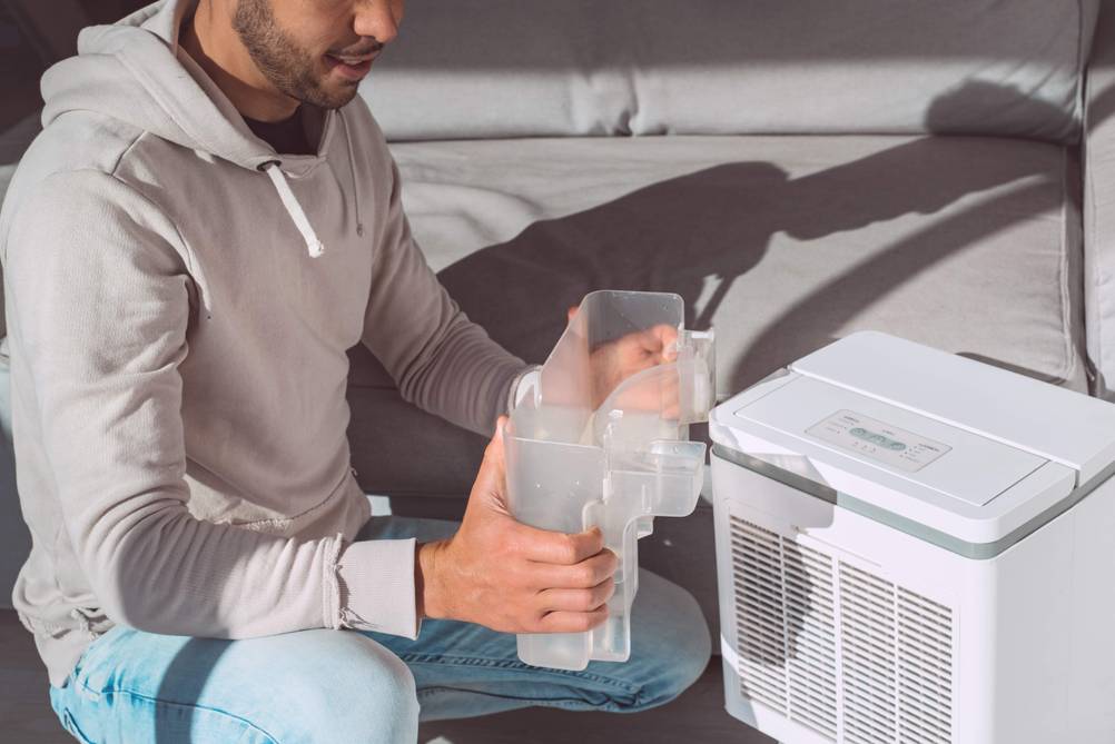 Luftbefeuchter-Verdunster im Test: Ein Mann hält den Wasserbehälter eines Luftbefeuchters in der Hand, das Gerät steht daneben.