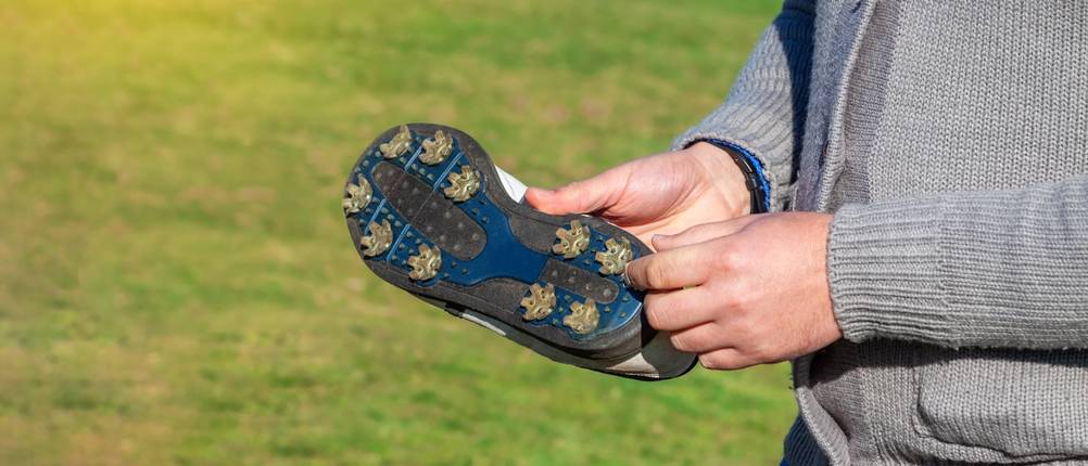 Herren-Golfschuhe-Test: Die Sohle der Golfschuhe werden so in der Hand gehalten, dass die Sohle ersichtlich ist.