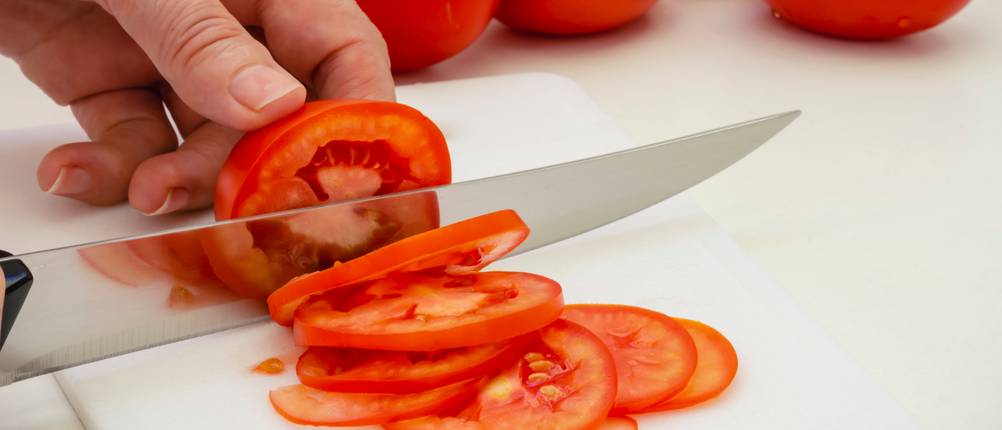 Tefal-Messer-Test: Tomaten werden auf einem Schneidebrett geschnitten.