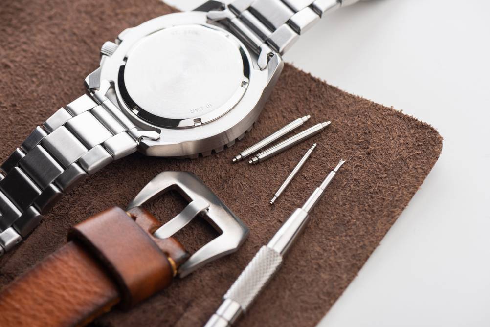 Sandstrahlgerät im Test: Herrenuhr mit Gliederarmband mit Werkzeug und Lederarmband daneben.