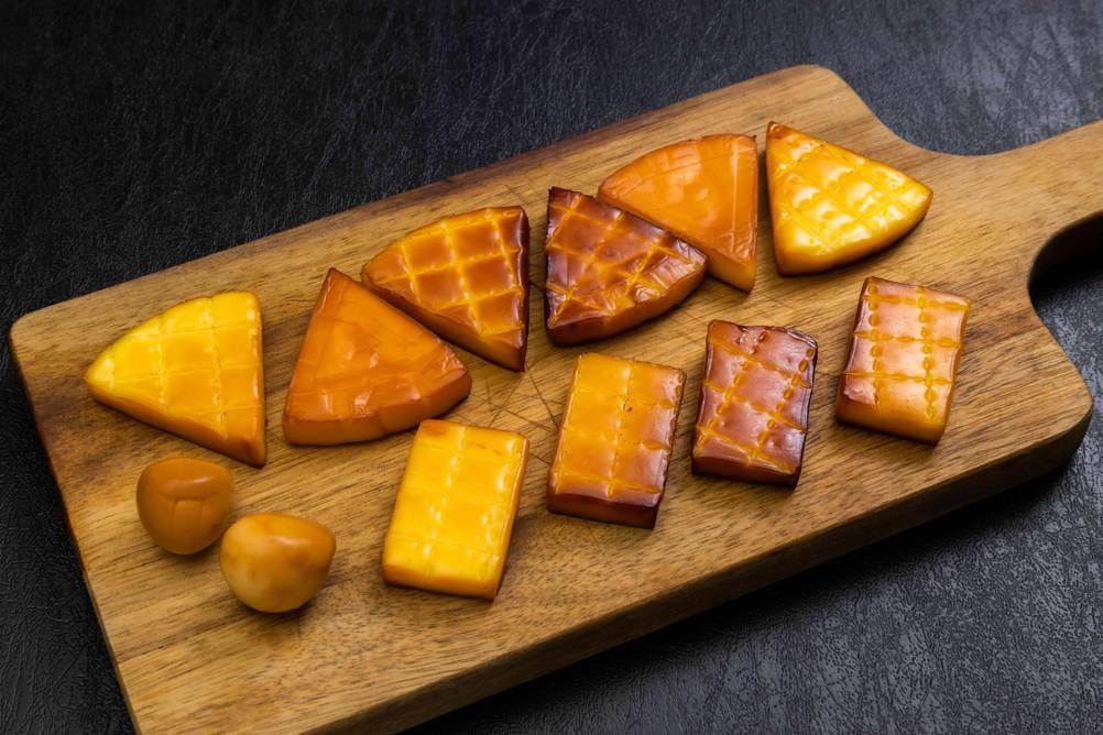 Räuchertonne im Test: ein Holzbrett, auf dem verschiedene Sorten geräucherter Käse präsentiert werden.