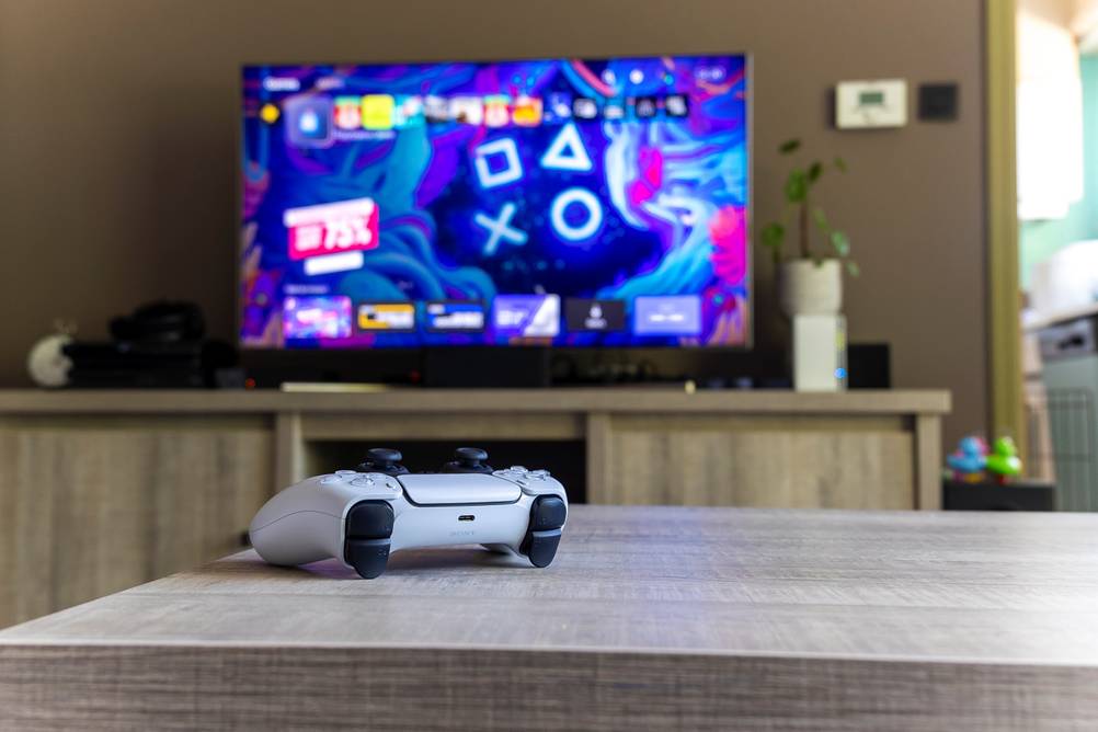 Sony-Fernseher-Test: TV-Gerät im Hintergrund und eine Handteil einer Spielkonsole im Vordergrund