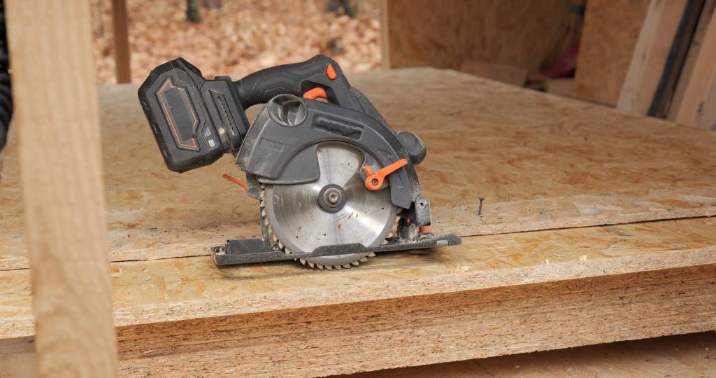 Akku-Handkreissäge im Test: Hier liegt eine kompakte Akku-Handkreissäge auf einem Stapel Grobspanplatten.