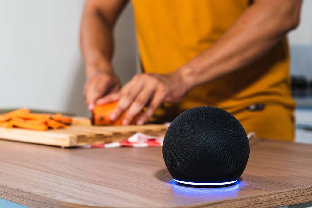 Klipsch-Lautsprecher im Test: Ein Mann schnibbelt Gemüse im Vordergrund steht eine aktive Alexa-Box.