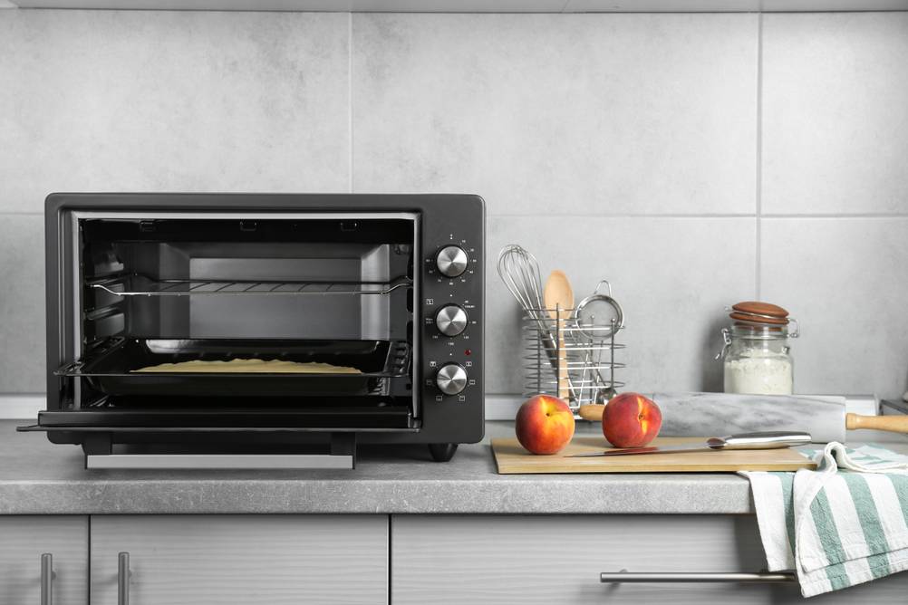 Mini-Backofen 30 Liter im Test: Ein Teig liegt auf dem Blech im offenen Ofen, daneben zwei Nektarinen auf einem Brett mit Messer.
