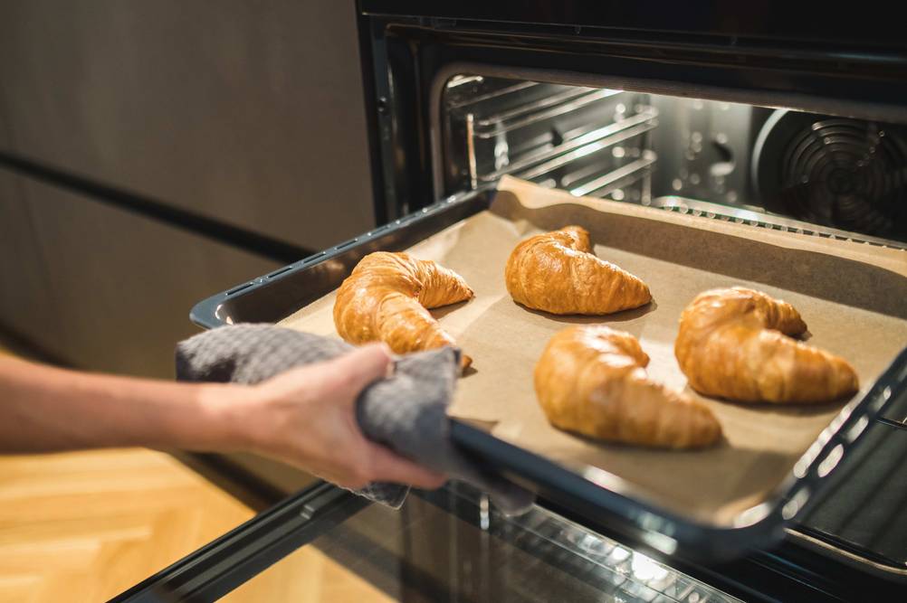 Exquisit-Backofen im Test: Croissonts auf einem Blech werden zum Aufbacken in den Backofen geschoben.
