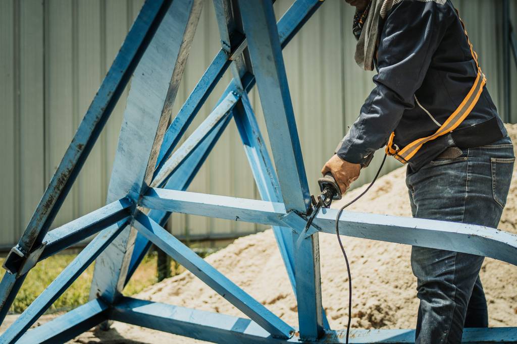 Bosch-Säbelsäge im Test: Ein Mann durchtrennt den Metallholm eines großen Metallgestells.