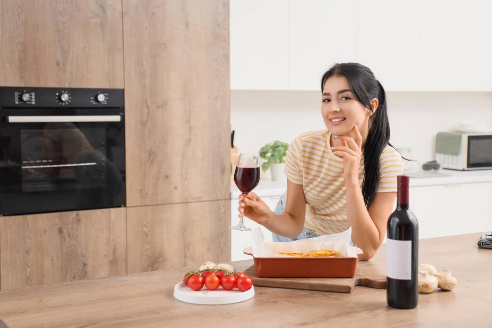 Mini-Backofen 45 Liter im Test: Frau mit Glas Rotwein vor einem Backofen der eingebaut ist.