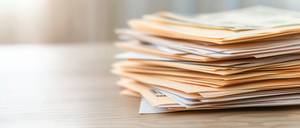 Rechnungsprogramme im Vergleich: Ein Stapel Akten liegt auf einem Tisch.