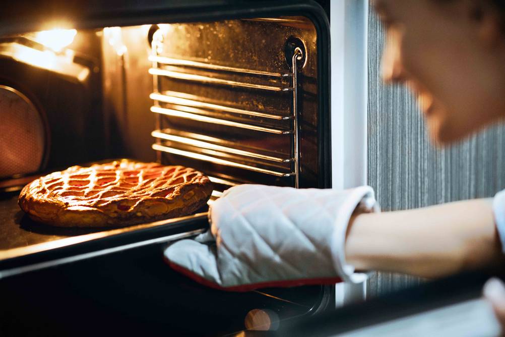 Beko-Herd im Test: Frau zieht Kuchen aus Backofen.
