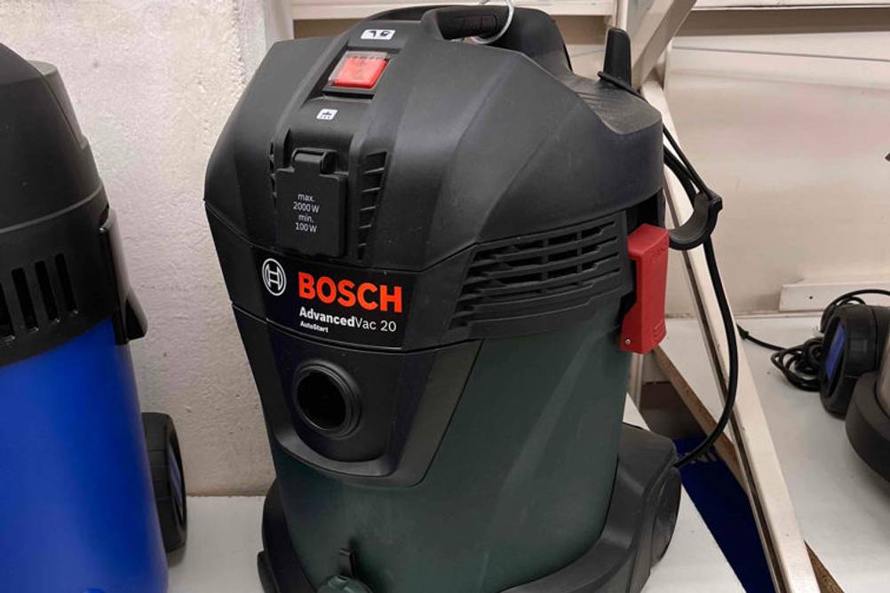 Beutelloser Bosch-Staubsauger im Test: ein Advancedvac-Staubsauger mit grünem Behälter steht neben einem anderen Modell in einem hellen Verkaufsbereich.