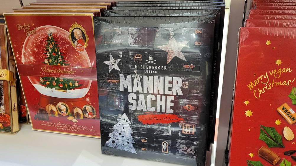 Mehrere getestete Adventskalender für Männer hintereinander neben anderen Produkten in einem Regal.