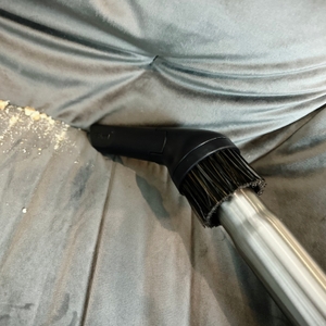 Die Fugendüse des AEG AB61H6SW saugt Krümel aus einer Sofaritze. Die Kombination mit der Bürste ist ebenfalls zu sehen.