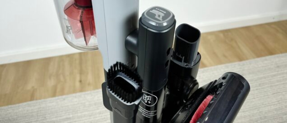 Der Stiel des AEG AP81AB25UG mit Zubehörhalterung zeigt verschiedene Aufsätze in Nahaufnahme. Die rote Zykloneinheit ist sichtbar.