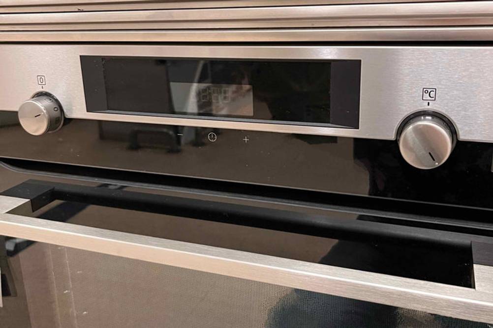 Nahaufnahme der LCD-Anzeige eines getesteten AEG-Backofens inklusive eines handlichen Edelstahl-Griffs und zweier Drehregler.