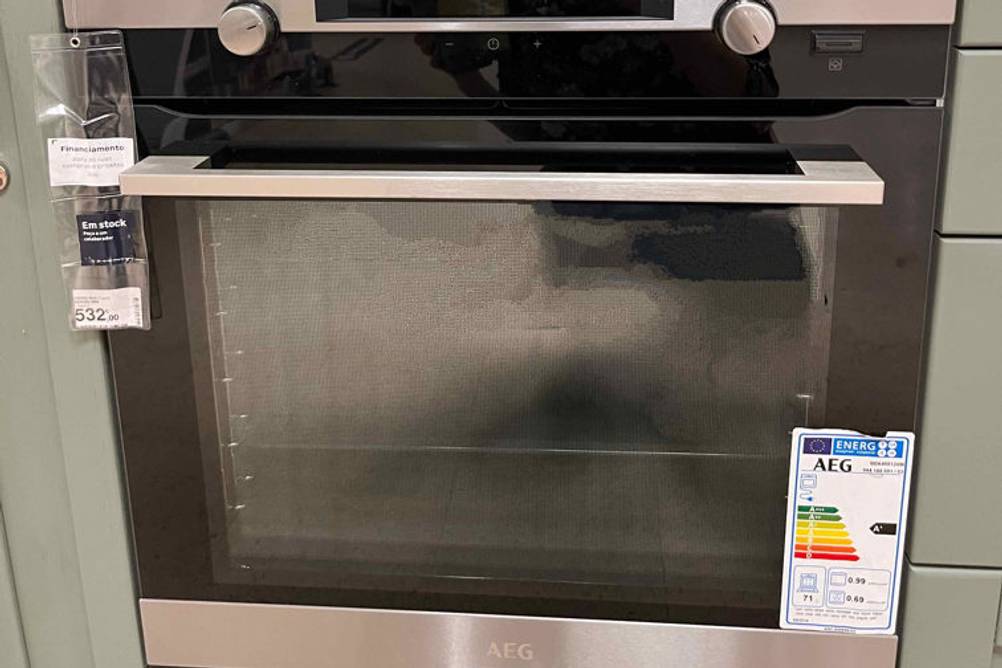 AEG-Backofen-Test: Vorderansicht eines Einbaubackofens inklusive Edelstahl-Griff sowie Anzeige und zweier Drehknöpfe, in einer Küchenzeile.