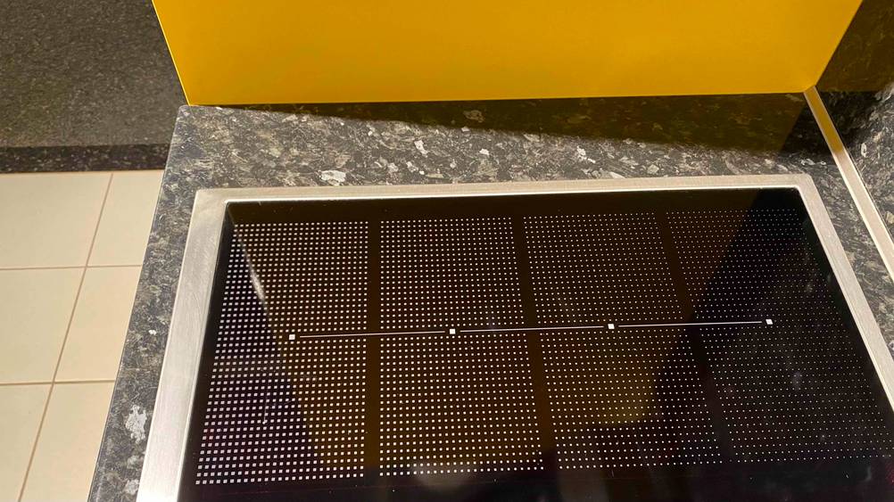 Im Test: Nahaufnahme der Kochfläche eines Induktionskochfelds mit Grafiken.
