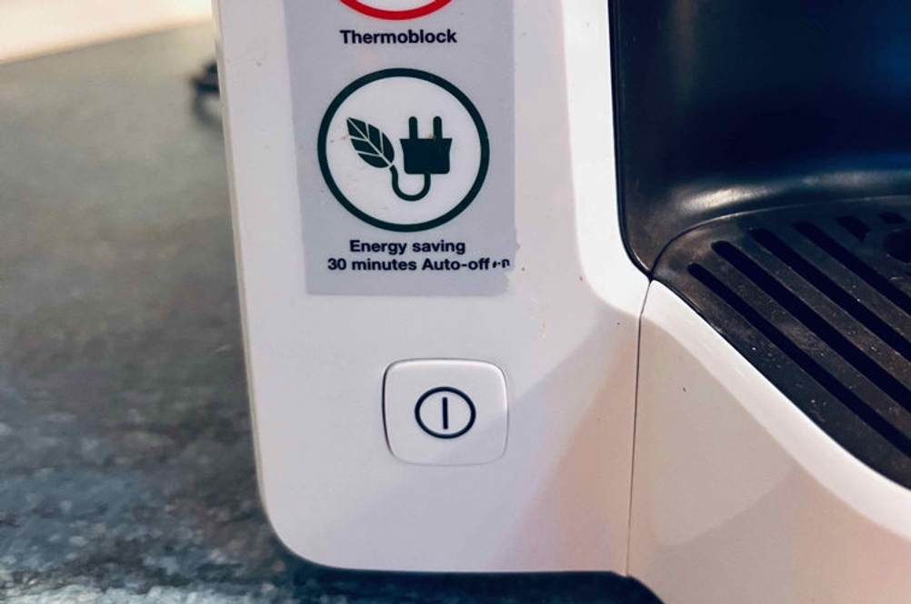 Kaffeemaschine-Test: Detailansicht der Einschalttaste einer weißen Kaffeemaschine mit Thermoblock.