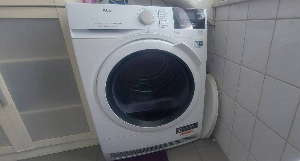 Ansicht von vorn eines Waschtrockners im Test, der sich in einem weißen Badezimmerbereich befindet.