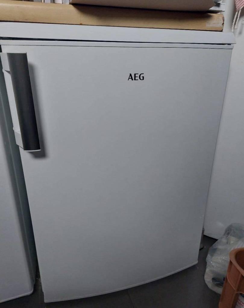 Kühlschrank ohne Gefrierfach im Test: Nahaufnahme von vorn auf einen weißen, geschlossenen AEG Kühlschrank unter einer Küchenarbeitsplatte aus Holz.
