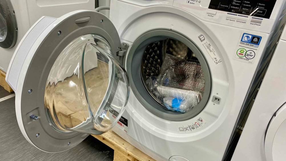 AEG-Waschtrockner getestet: Ein Gerät mit geöffneter Klappe, im Inneren Zubehör.