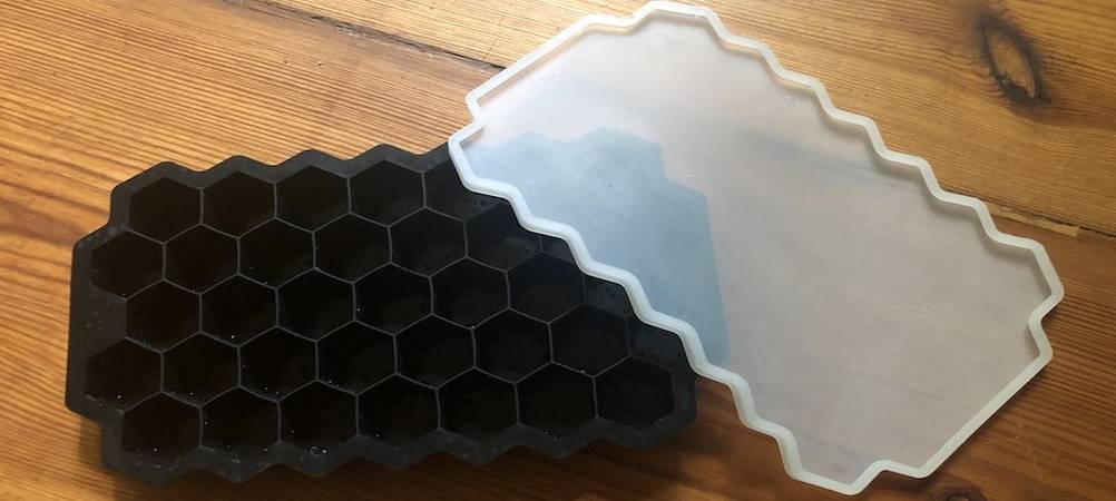 Eine schwarze Eiswürfelform mit Deckel auf einem Holzuntergrund