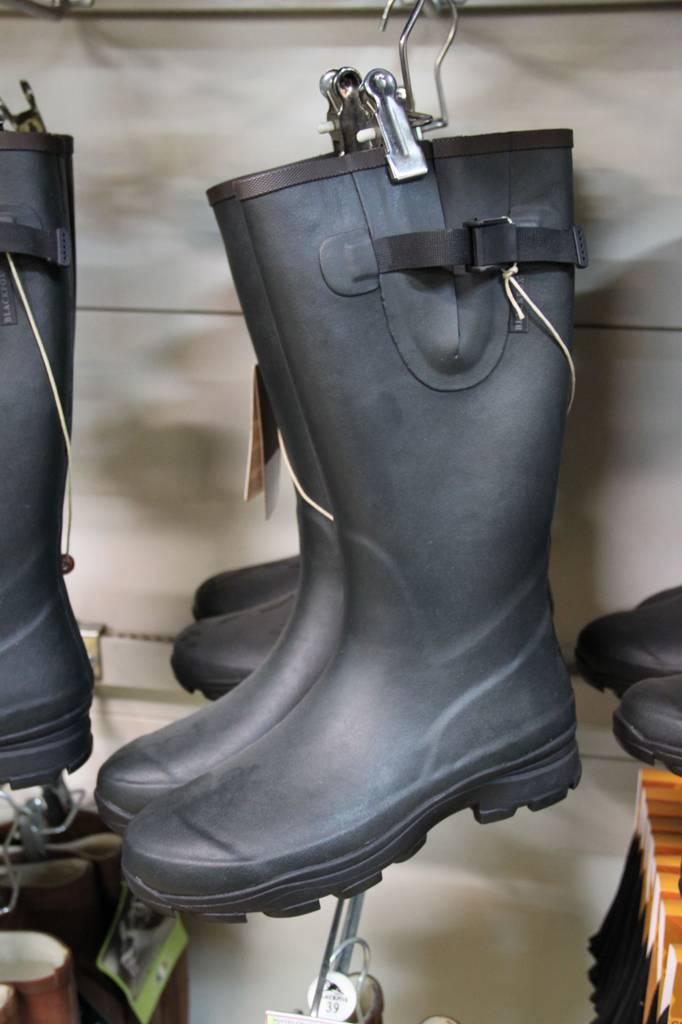 Aigle-Gummistiefel-Test: ein paar schwarze Gummistiefel mit Lasche zum Regulieren der Schaftweite hängen im Regal