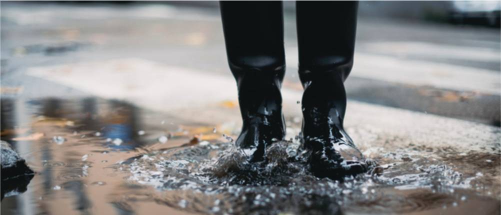 Aigle-Gummistiefel-Test: Person in schwarzen Gummistiefeln in einer Pfütze.