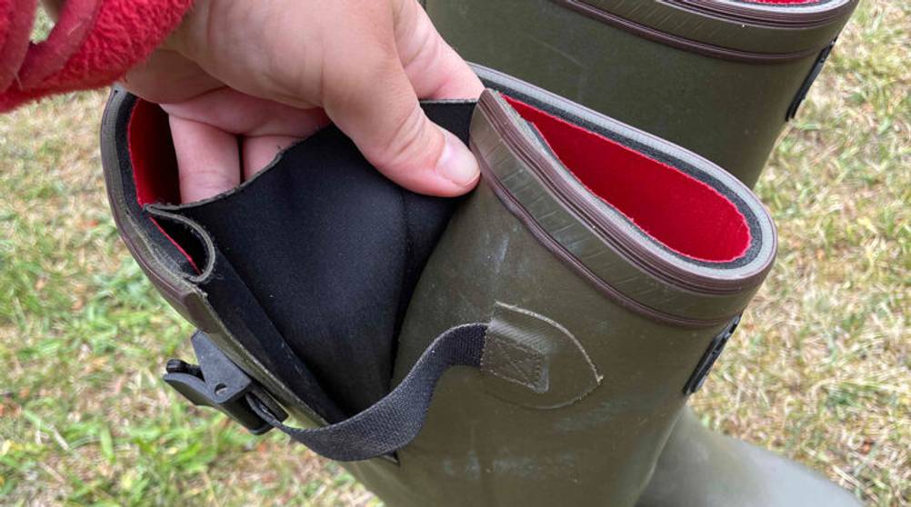 Grüne Neopren-Gummistiefel im Test: Hand zeigt eine mit schwarzem, elastischem Stoff versehene Schafterweiterung.