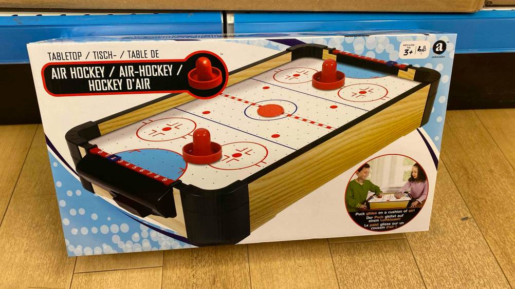 Getestetes Air-Hockey liegt verpackt an einem Geschäftsregal an.