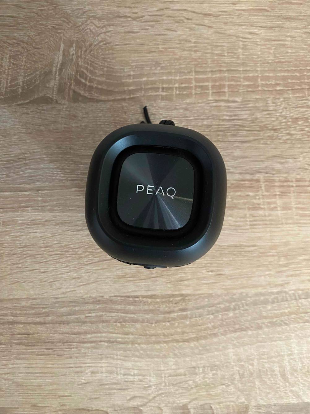 Ein getesteter AirPlay-Lautsprecher der Marke Peaq von oben auf einer Holzoberfläche.