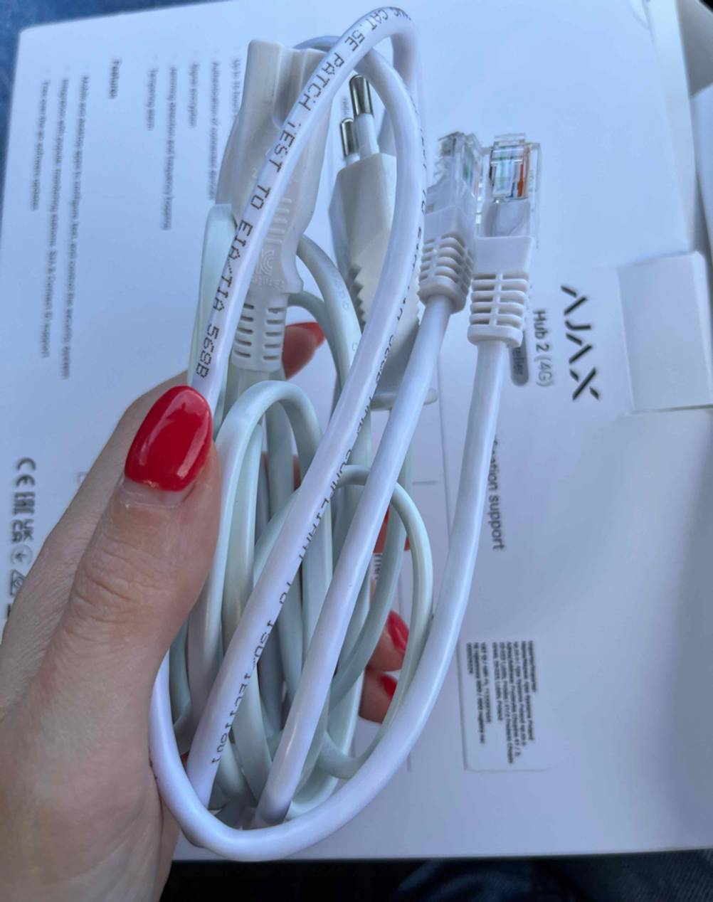 Kabel der getesteten Ajax-Alarmanlage werden in der Hand gehalten.