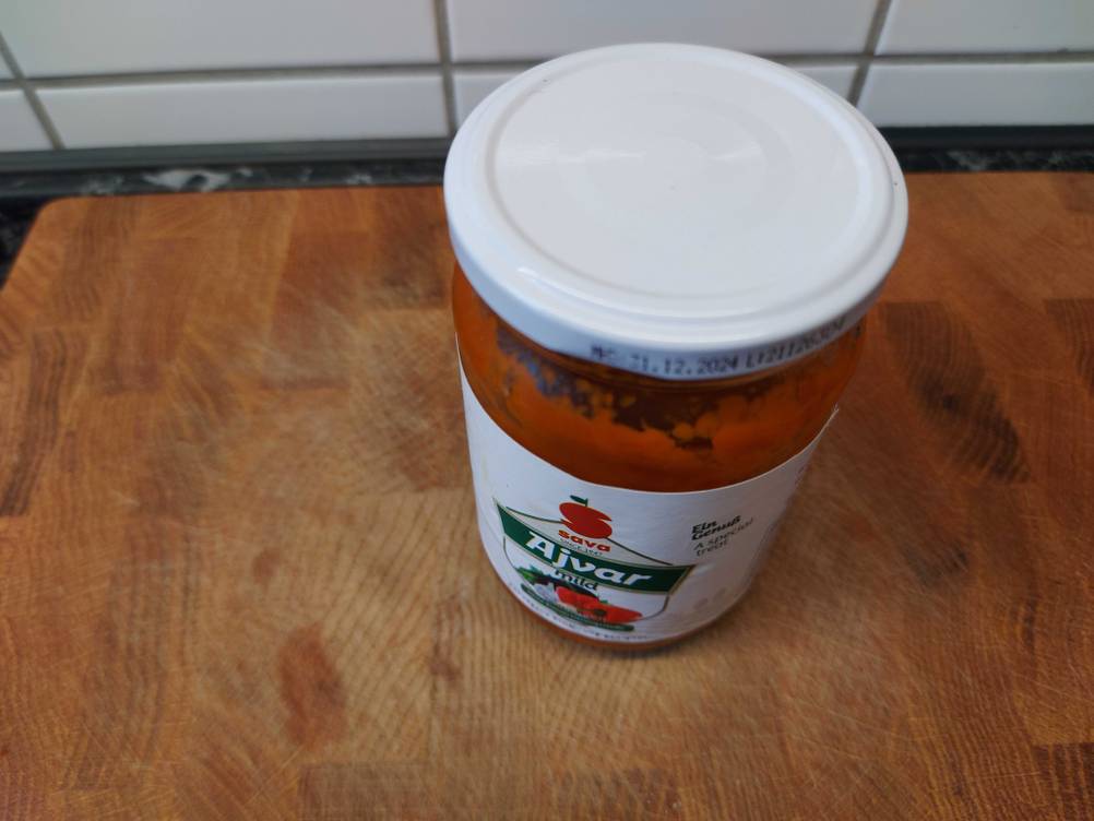 Im Test: Ein Glas Ajvar von schräg oben auf einem Holzbrett.
