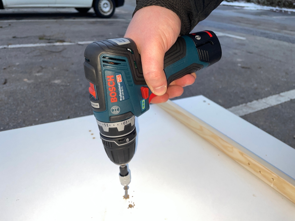 Der Bosch GSR 12V-35 FC wird beim Bohren in eine helle Oberfläche gehalten. Die kompakte Bauform und ergonomische Griffgestaltung ermöglichen eine sichere Führung während der Arbeit.