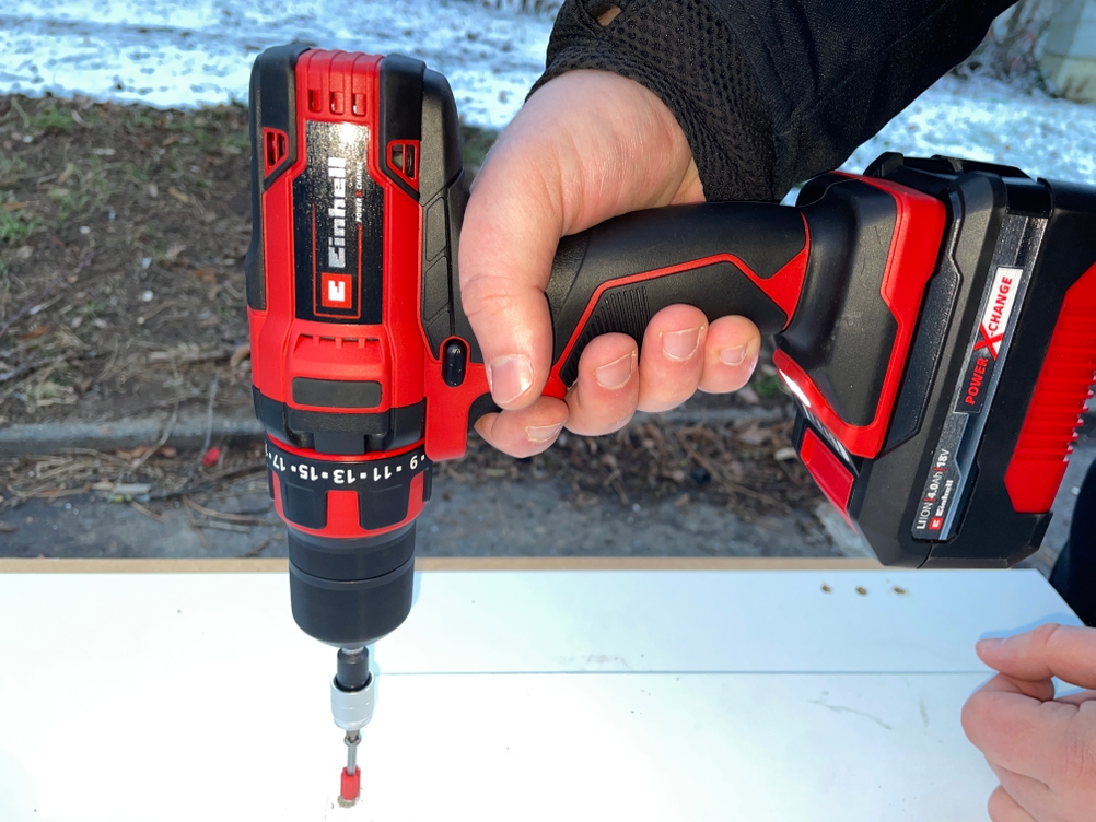 Einhell Akku-Bohrschrauber beim Schraubeinsatz auf einer weißen Oberfläche im Außenbereich.