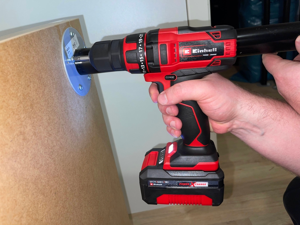 Einhell Akku-Bohrschrauber beim Festschrauben eines Flanschs an eine Holzplatte.