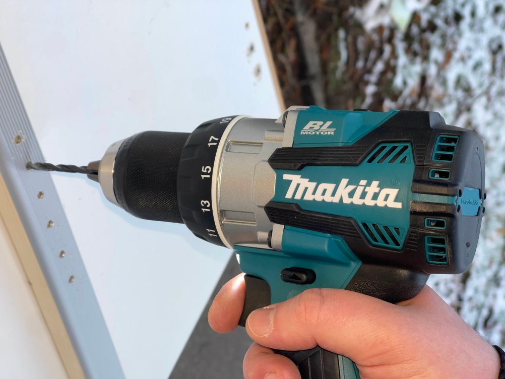 Makita Akku-Bohrschrauber während des Bohrens auf einer beschichteten Arbeitsfläche mit Schnee im Hintergrund.