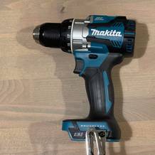 Makita Akku-Bohrschrauber im ausgeschalteten Zustand, von der Seite fotografiert auf hellem Untergrund liegend.